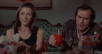 Movie still from “The Last Movie” (1971), directed by Dennis Hopper – A man and a woman sitting at a table with a drink; Medium shot, Over the shoulder angle