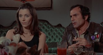 Movie still from “The Last Movie” (1971), directed by Dennis Hopper – A man and a woman sitting at a table with drinks; Medium shot, Low angle