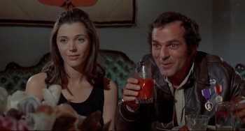 Movie still from “The Last Movie” (1971), directed by Dennis Hopper – A man and a woman sitting next to each other holding a drink; Medium shot, High angle