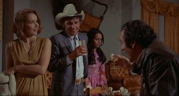 Movie still from “The Last Movie” (1971), directed by Dennis Hopper – A man in a cowboy hat is holding a glass of wine; Medium shot, Over the shoulder angle