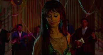 Movie still from “The Last Movie” (1971), directed by Dennis Hopper – A woman with long black hair wearing a green dress; Close Up shot, Over the shoulder angle