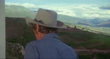 Movie still from “The Last Movie” (1971), directed by Dennis Hopper – A man wearing a cowboy hat looking out over a valley; Medium shot, Over the shoulder angle