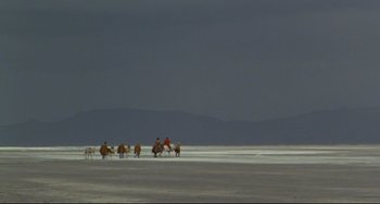 Movie still from “The Last Movie” (1971), directed by Dennis Hopper – A group of people riding horses across a beach; Extreme Wide shot, High angle