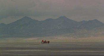Movie still from “The Last Movie” (1971), directed by Dennis Hopper – A group of people riding horses across a large expanse of land; Extreme Wide shot, High angle