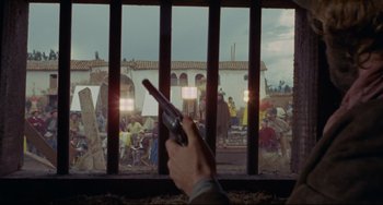 Movie still from “The Last Movie” (1971), directed by Dennis Hopper – A person holding a cell phone in front of a window; Wide shot, Over the shoulder angle