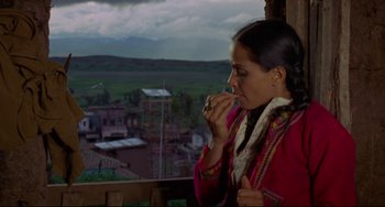 Movie still from “The Last Movie” (1971), directed by Dennis Hopper – A woman eating a piece of food while standing on a balcony; Medium shot, High angle