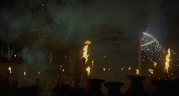 Movie still from “The Last Movie” (1971), directed by Dennis Hopper – A group of people standing in front of a fire; Extreme Wide shot, Low angle