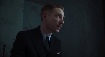 Movie still from “The Little Stranger” (2018), directed by Lenny Abrahamson – A man wearing a suit and tie looking up; Close Up shot, Low angle