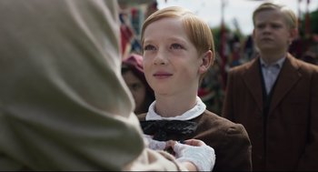 Movie still from “The Little Stranger” (2018), directed by Lenny Abrahamson – A young boy wearing a bow tie looks up at a crowd; Close Up shot, Over the shoulder angle