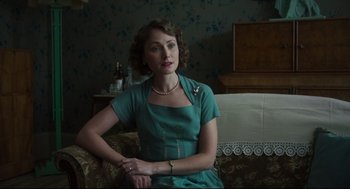 Movie still from “The Little Stranger” (2018), directed by Lenny Abrahamson – A woman sitting on a couch in a room; Medium shot, Low angle