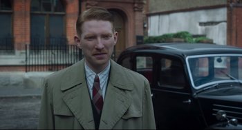 Movie still from “The Little Stranger” (2018), directed by Lenny Abrahamson – A man in a suit and tie standing in front of a car; Close Up shot, Over the shoulder angle