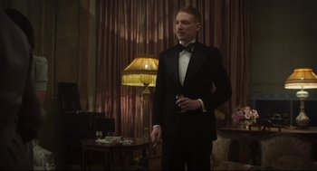 Movie still from “The Little Stranger” (2018), directed by Lenny Abrahamson – A man in a tuxedo standing in a living room; Medium shot, Low angle