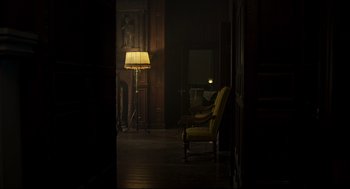 Movie still from “The Little Stranger” (2018), directed by Lenny Abrahamson – A chair and a lamp in a dark room lit by a lamp; Wide shot, High angle