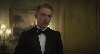 Movie still from “The Little Stranger” (2018), directed by Lenny Abrahamson – A man in a tuxedo standing in front of a painting; Close Up shot, Low angle
