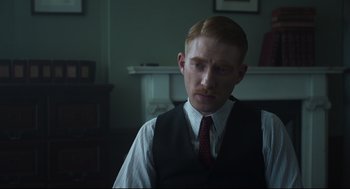 Movie still from “The Little Stranger” (2018), directed by Lenny Abrahamson – A man with red hair wearing a vest and a tie; Close Up shot, Over the shoulder angle