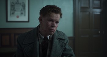 Movie still from “The Little Stranger” (2018), directed by Lenny Abrahamson – A man in a coat and tie sitting in a room; Close Up shot, Low angle