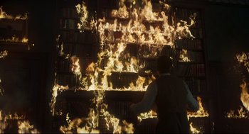 Movie still from “The Little Stranger” (2018), directed by Lenny Abrahamson – A man standing in front of a bookshelf on fire; Medium shot, High angle