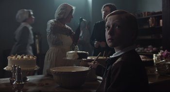 Movie still from “The Little Stranger” (2018), directed by Lenny Abrahamson – A young boy sitting at a table with a bowl of food; Medium shot, Over the shoulder angle
