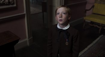 Movie still from “The Little Stranger” (2018), directed by Lenny Abrahamson – A young boy wearing a suit and a medal; Close Up shot, High angle