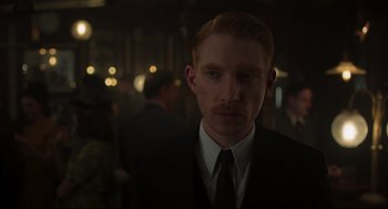 Movie still from “The Little Stranger” (2018), directed by Lenny Abrahamson – A man in a suit and tie in a dark room; Close Up shot, Over the shoulder angle