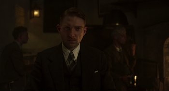 Movie still from “The Little Stranger” (2018), directed by Lenny Abrahamson – A man wearing a suit and tie in a dark room; Close Up shot, Low angle