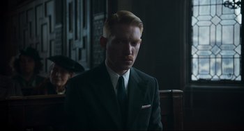 Movie still from “The Little Stranger” (2018), directed by Lenny Abrahamson – A man wearing a suit and tie in a dark room; Close Up shot, Over the shoulder angle