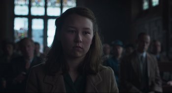 Movie still from “The Little Stranger” (2018), directed by Lenny Abrahamson – A woman in a brown jacket is looking at the camera; Close Up shot, Over the shoulder angle