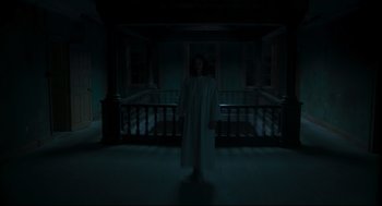 Movie still from “The Little Stranger” (2018), directed by Lenny Abrahamson – A person standing in a dark room in front of a railing; Wide shot, Low angle