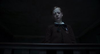 Movie still from “The Little Stranger” (2018), directed by Lenny Abrahamson – A young boy in a suit and tie looking out a railing; Medium shot, Low angle