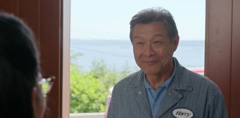 Movie still from “Always Be My Maybe” (2019), directed by Nahnatchka Khan – An older man standing in front of a window; Medium shot, Over the shoulder angle