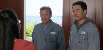 Movie still from “Always Be My Maybe” (2019), directed by Nahnatchka Khan – A man wearing a denim jacket with a name tag on it; Medium shot, Over the shoulder angle