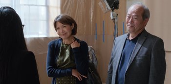 Movie still from “Always Be My Maybe” (2019), directed by Nahnatchka Khan – A woman standing next to a man holding a purse; Medium shot, Over the shoulder angle