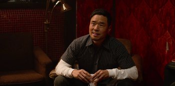 Movie still from “Always Be My Maybe” (2019), directed by Nahnatchka Khan – A man sitting in a chair with his arm in a cast; Medium shot, Over the shoulder angle