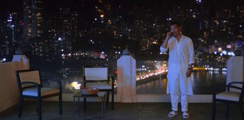 Movie still from “Always Be My Maybe” (2019), directed by Nahnatchka Khan – A man standing on a balcony talking on a phone; Wide shot, Low angle