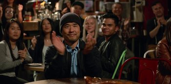 Movie still from “Always Be My Maybe” (2019), directed by Nahnatchka Khan – A group of people sitting at a table clapping; Medium shot, Over the shoulder angle
