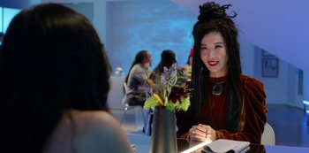 Movie still from “Always Be My Maybe” (2019), directed by Nahnatchka Khan – A woman sitting at a table with a vase of flowers; Close Up shot, Over the shoulder angle