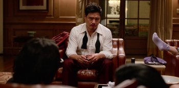Movie still from “Always Be My Maybe” (2019), directed by Nahnatchka Khan – A man sitting on a leather chair holding a glass of wine; Medium shot, Over the shoulder angle