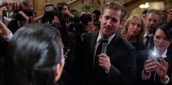 Movie still from “Always Be My Maybe” (2019), directed by Nahnatchka Khan – A man in a black suit is being interviewed by a group of people; Close Up shot, Over the shoulder angle