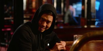 Movie still from “Always Be My Maybe” (2019), directed by Nahnatchka Khan – A man wearing a black hooded sweatshirt sitting at a table; Close Up shot, Over the shoulder angle