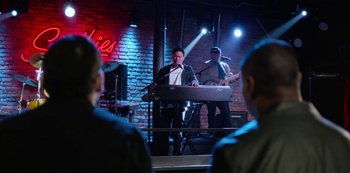 Movie still from “Always Be My Maybe” (2019), directed by Nahnatchka Khan – A man playing a keyboard in front of a crowd; Wide shot, Over the shoulder angle