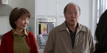 Movie still from “Always Be My Maybe” (2019), directed by Nahnatchka Khan – An older man standing next to an older woman in a kitchen; Medium shot, Over the shoulder angle