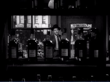 Movie still from “The Lost Weekend” (1945), directed by Billy Wilder – A black and white photo of a man behind a bar; Medium shot, Low angle