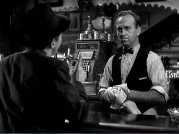 Movie still from “The Lost Weekend” (1945), directed by Billy Wilder – A man and a woman sitting in front of a cash register; Medium shot, Over the shoulder angle
