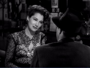 Movie still from “The Lost Weekend” (1945), directed by Billy Wilder – A woman sitting next to a man wearing a hat; Close Up shot, Over the shoulder angle