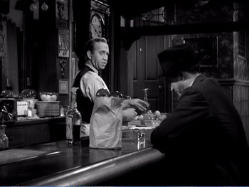 Movie still from “The Lost Weekend” (1945), directed by Billy Wilder – A man standing at a counter in a bar; Medium shot, Over the shoulder angle