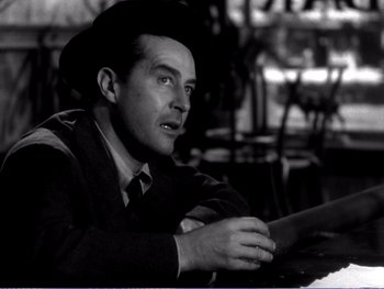 Movie still from “The Lost Weekend” (1945), directed by Billy Wilder – A man wearing a hat sitting at a table in a restaurant; Close Up shot, Low angle