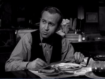 Movie still from “The Lost Weekend” (1945), directed by Billy Wilder – A man sitting at a table with a plate in front of him; Medium shot, Over the shoulder angle