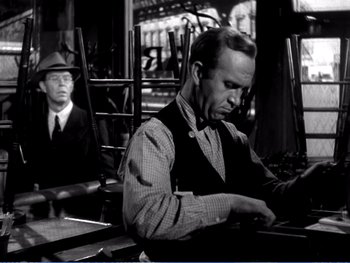 Movie still from “The Lost Weekend” (1945), directed by Billy Wilder – A man sitting at a table in front of another man in a hat; Medium shot, Over the shoulder angle