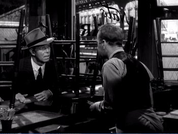 Movie still from “The Lost Weekend” (1945), directed by Billy Wilder – A man wearing a hat talking to another man in a suit; Medium shot, Over the shoulder angle
