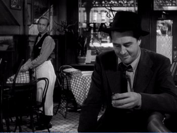 Movie still from “The Lost Weekend” (1945), directed by Billy Wilder – A man in a suit and tie looking at his cell phone; Medium shot, Over the shoulder angle
